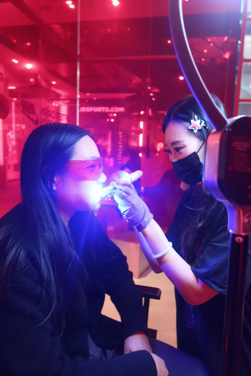 A gem being cured under a blue light while the client wears protective glasses