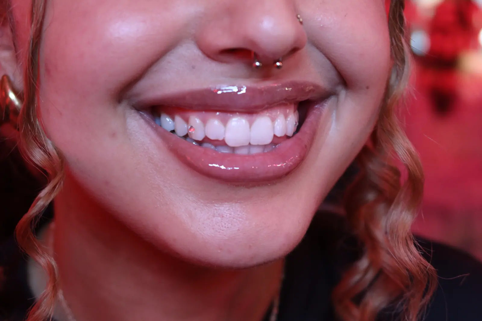 A wide smile with a small gem, septum ring in frame